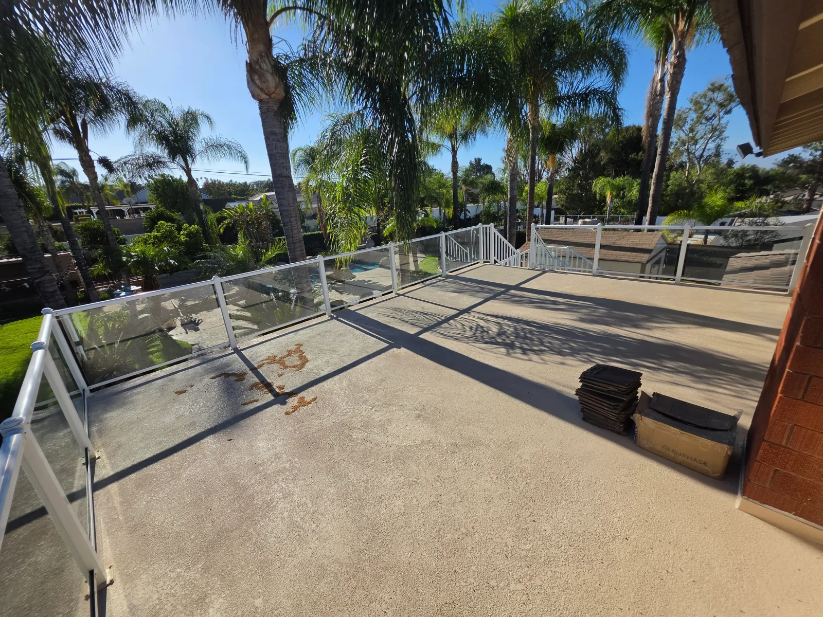 Concrete deck with white aluminum and glass railings, waterfront view, palm trees