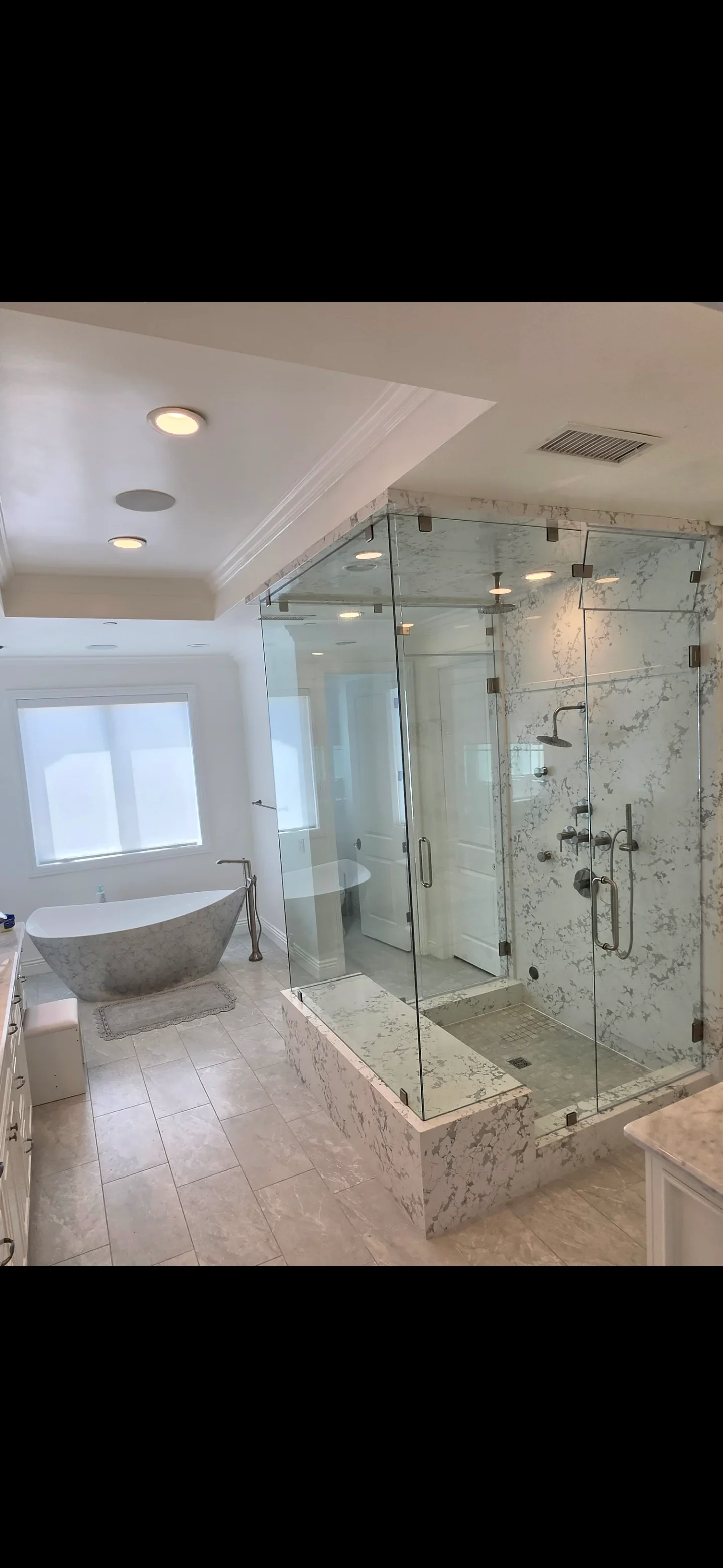 Marble bathroom with frameless glass shower, freestanding tub, and tile flooring