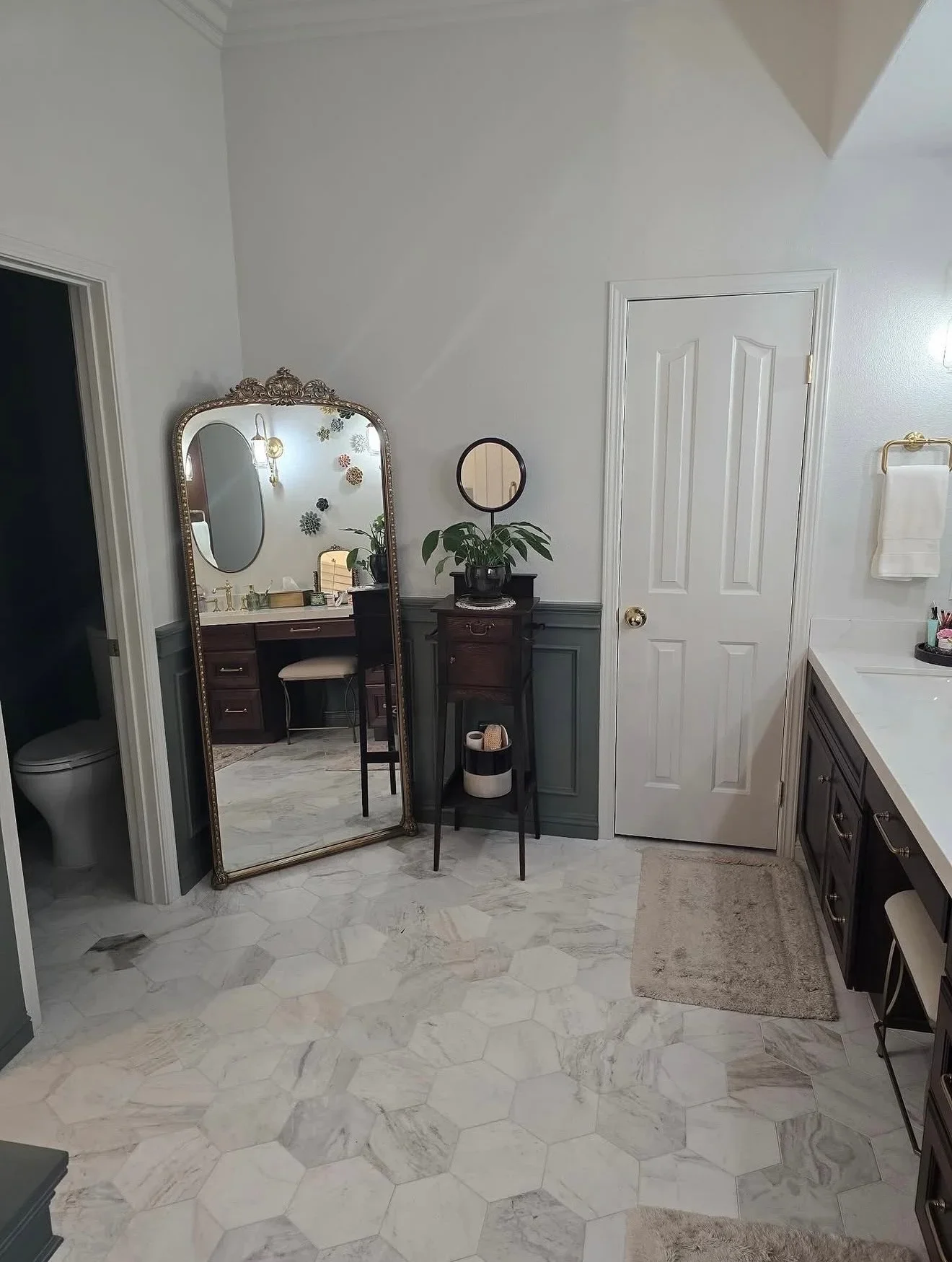 Marble hexagon tile floor, white walls with wainscoting, dark wood vanities, brass hardware
