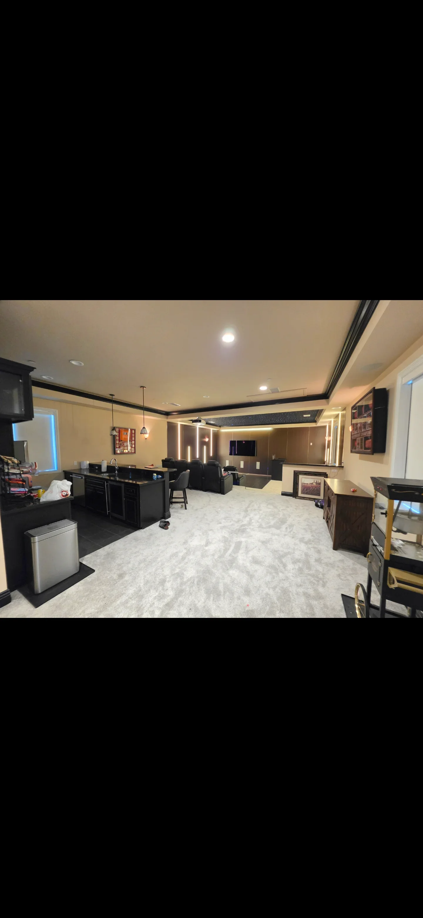 Finished basement with black bar cabinetry, vinyl flooring, coffered ceiling with LED lighting, and entertainment space