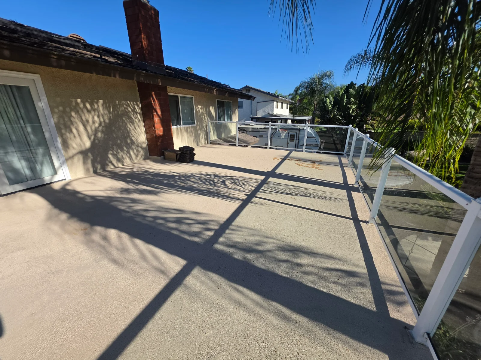 Finished concrete patio with white aluminum and glass railing system, control joints visible